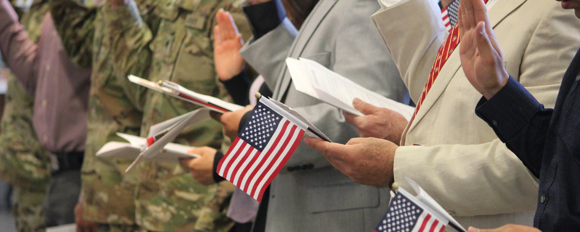 People raise their hands and hold U.S. flags at a U.S. citizen naturalization ceremony