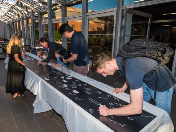 Current students and alumni all sign their name on the foundational steel slab during the College's Signing Ceremony