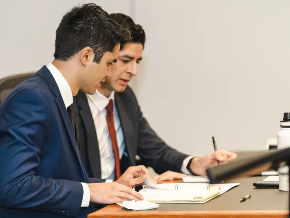 two students wearing suits comparing notes