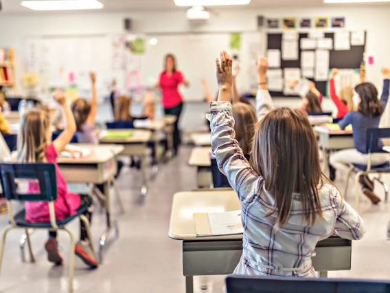 kids in class with their hands raised 