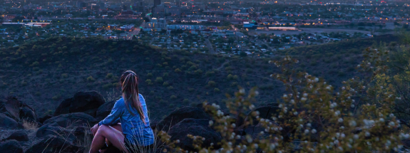 Student sitting on a foothill, overlooking the city