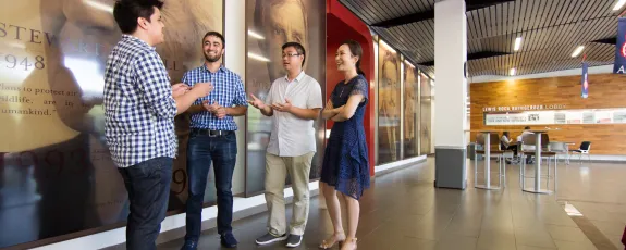 4 students in the University of Arizona Law JD for Non-U.S. Lawyers program talk in the lobby of the law school
