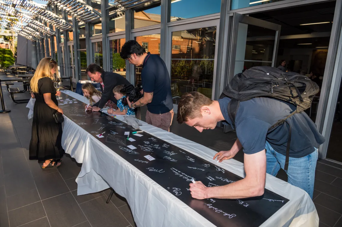 Current students and alumni all sign their name on the foundational steel slab during the College's Signing Ceremony