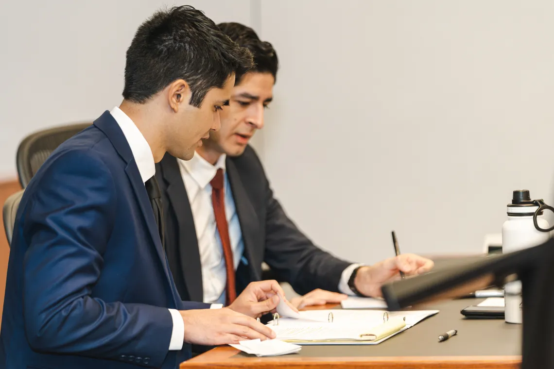 two students wearing suits comparing notes