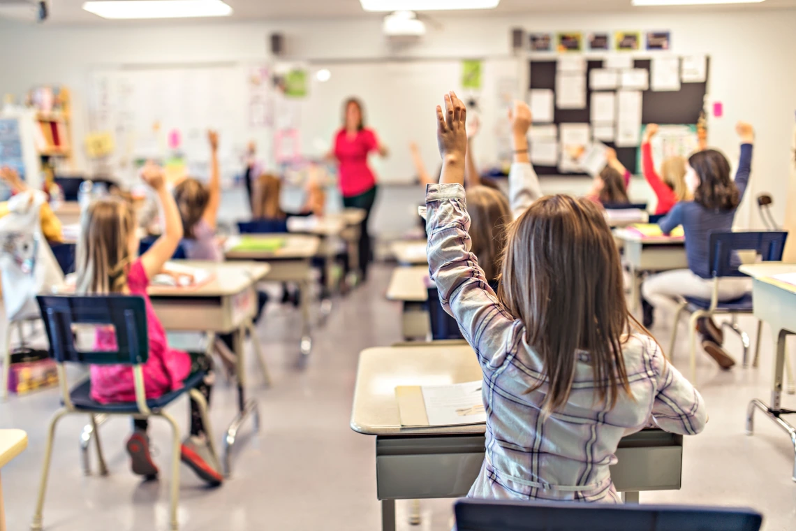 kids in class with their hands raised 