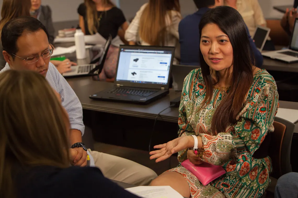 A woman sits in a classroom talking to other students