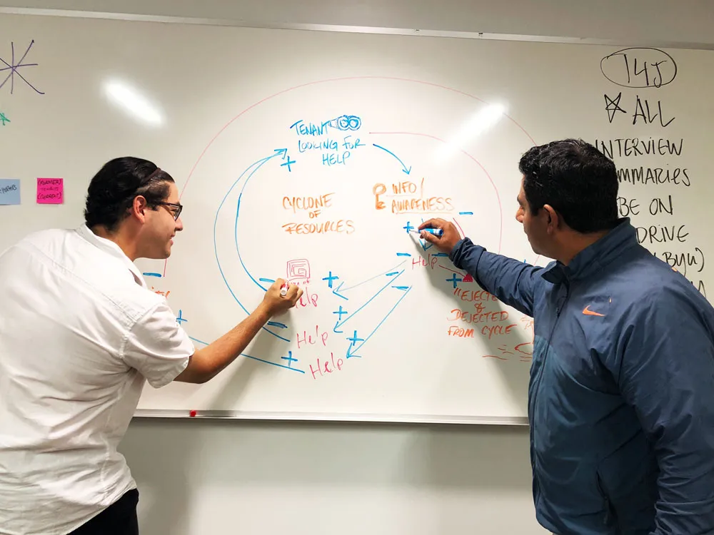 Two men draw on a whiteboard