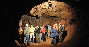 A group of people in hard hats explore a mine